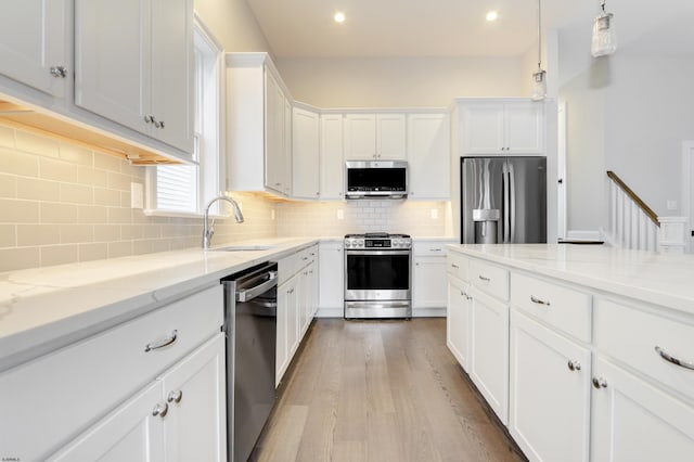 kitchen featuring backsplash, sink, white cabinets, and appliances with stainless steel finishes