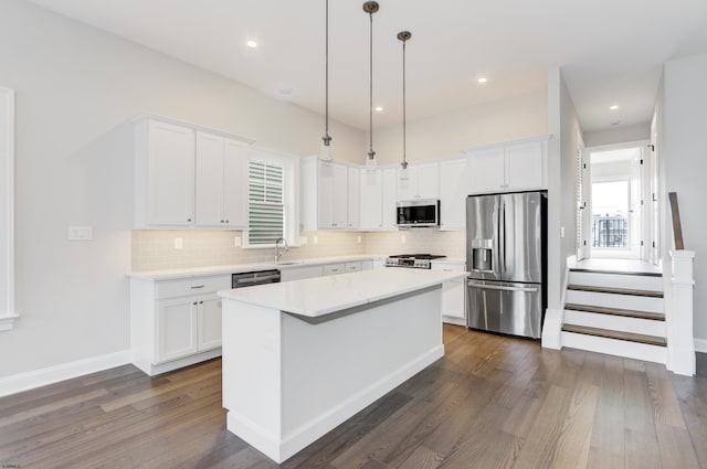 kitchen featuring white cabinetry, a center island, decorative light fixtures, and appliances with stainless steel finishes