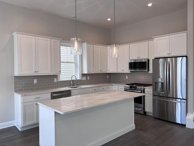 kitchen with white cabinets, decorative light fixtures, a center island, and appliances with stainless steel finishes