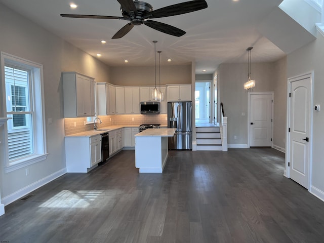 kitchen featuring appliances with stainless steel finishes, a kitchen island, sink, pendant lighting, and white cabinetry