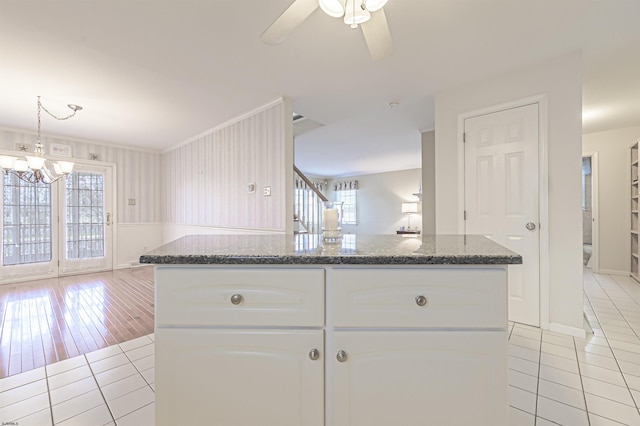 kitchen featuring ceiling fan with notable chandelier, a center island, white cabinetry, and light tile patterned floors