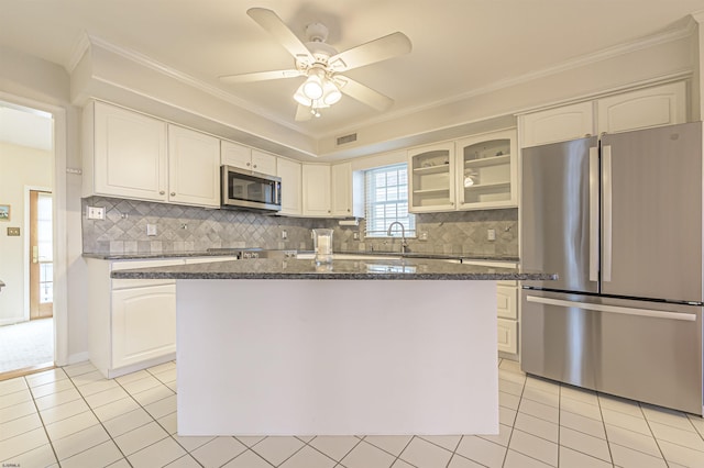 kitchen featuring backsplash, white cabinets, ceiling fan, appliances with stainless steel finishes, and light tile patterned flooring