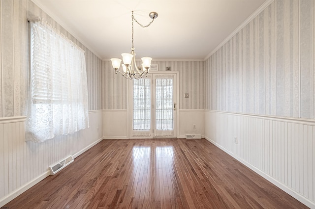 unfurnished dining area featuring an inviting chandelier, wood-type flooring, and ornamental molding