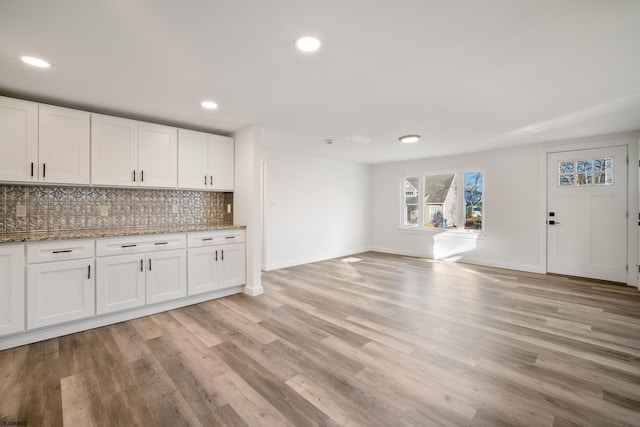 kitchen with decorative backsplash, white cabinetry, and light hardwood / wood-style flooring