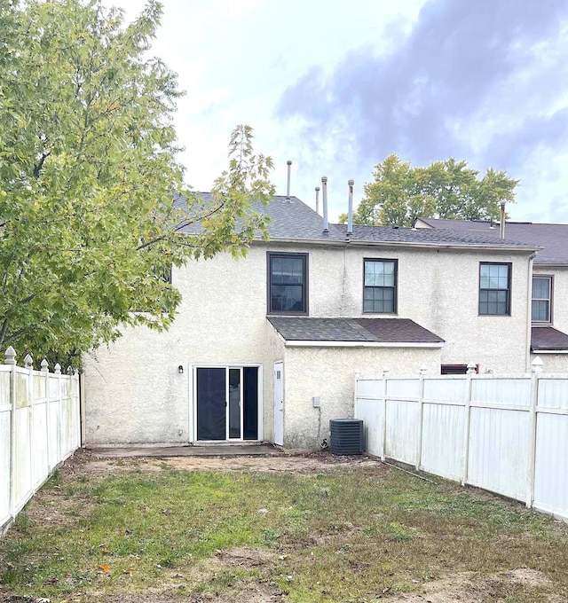 back of property with a yard and central AC unit