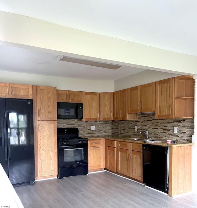 kitchen with sink, backsplash, light hardwood / wood-style flooring, and black appliances