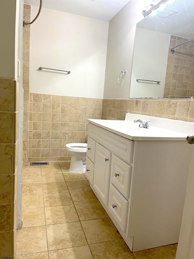 bathroom with vanity, toilet, and tile walls