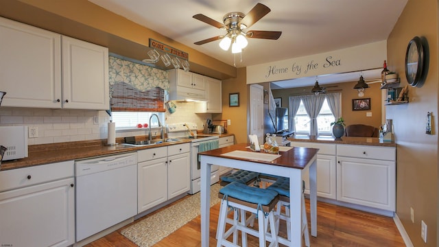 kitchen with backsplash, white cabinetry, sink, and white appliances