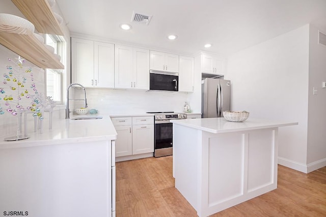 kitchen with a center island, sink, stainless steel appliances, light hardwood / wood-style flooring, and white cabinets