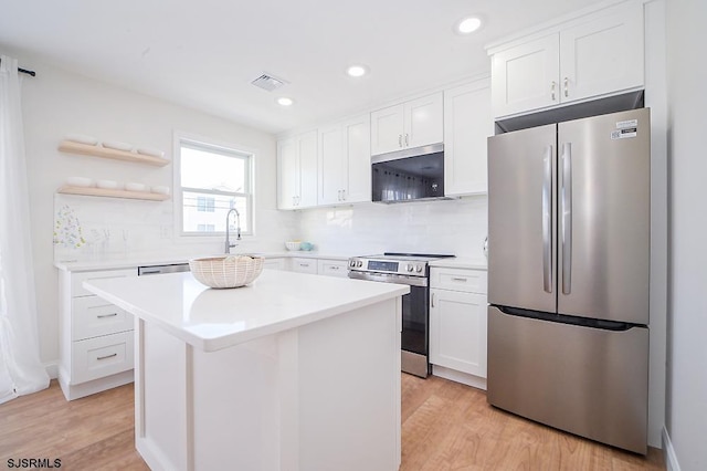 kitchen featuring white cabinets, a center island, stainless steel appliances, and light hardwood / wood-style floors