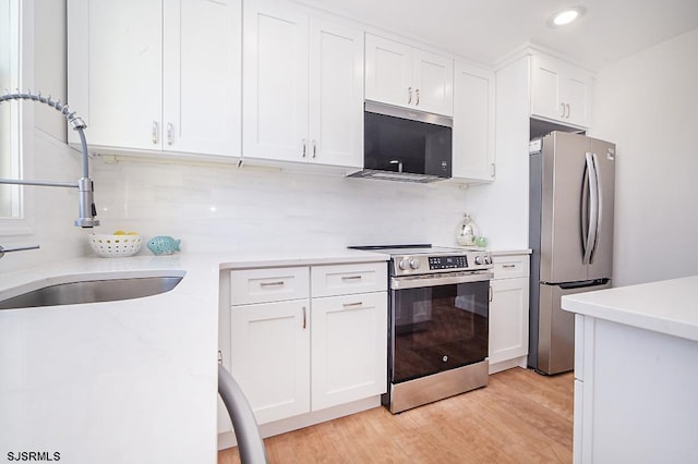 kitchen featuring backsplash, stainless steel appliances, sink, light hardwood / wood-style flooring, and white cabinetry