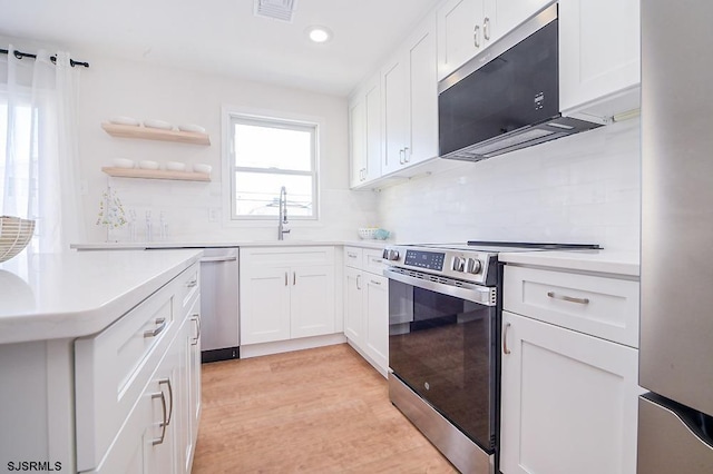 kitchen featuring sink, white cabinets, stainless steel appliances, and light hardwood / wood-style flooring