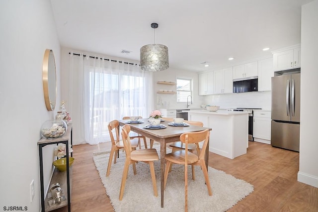 dining space with sink and light wood-type flooring