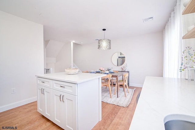 kitchen with light hardwood / wood-style floors, white cabinetry, hanging light fixtures, and a kitchen island