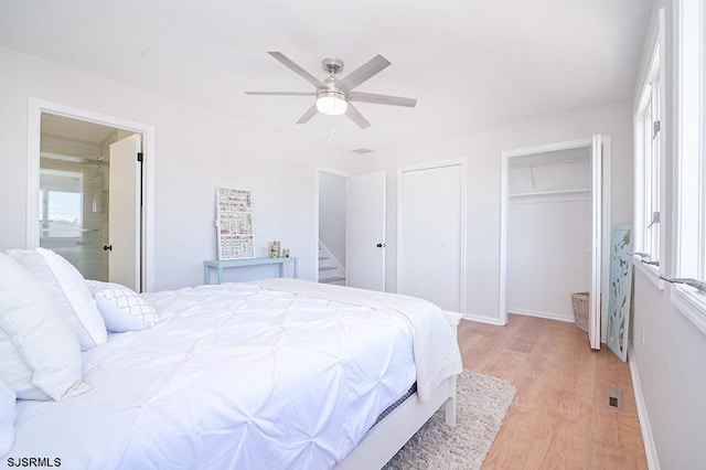 bedroom featuring light hardwood / wood-style flooring, ceiling fan, and multiple closets