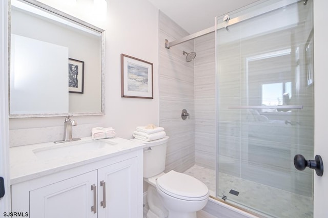 bathroom with vanity, toilet, and a shower with door