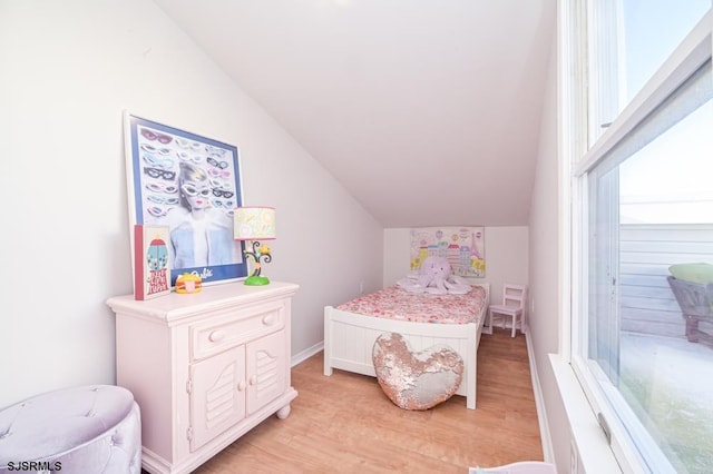 bedroom with light hardwood / wood-style floors, vaulted ceiling, and multiple windows