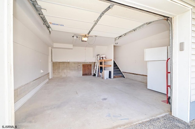 garage with a garage door opener and white refrigerator