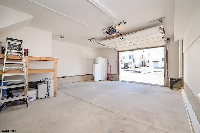 garage featuring white refrigerator and a garage door opener