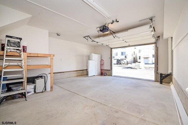 garage featuring white refrigerator and a garage door opener