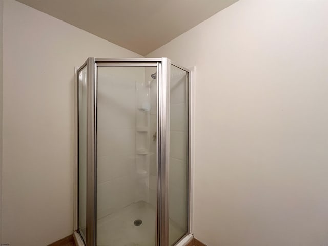 bathroom with a shower with shower door and lofted ceiling