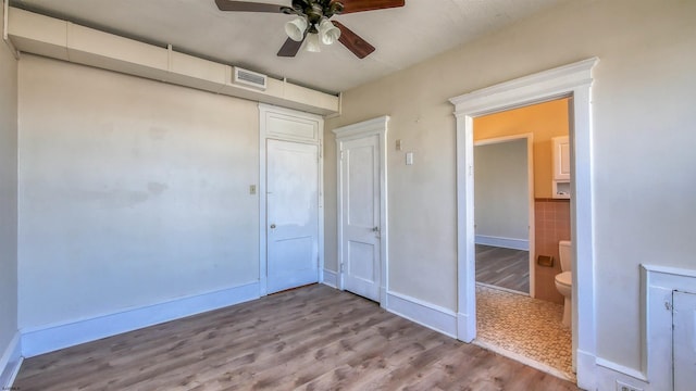 unfurnished bedroom featuring ensuite bath, ceiling fan, and light wood-type flooring