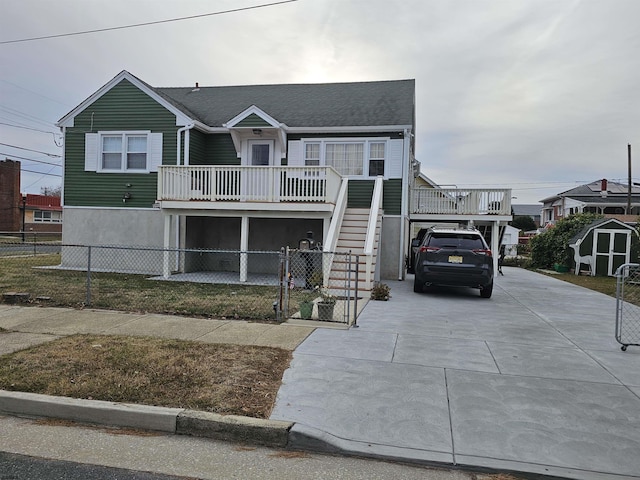 view of front facade with concrete driveway, stairway, fence, and a balcony