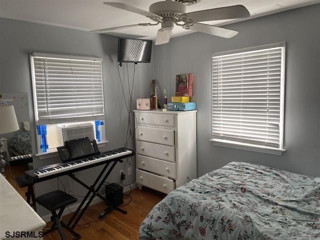 bedroom featuring a ceiling fan, cooling unit, and dark wood-style flooring
