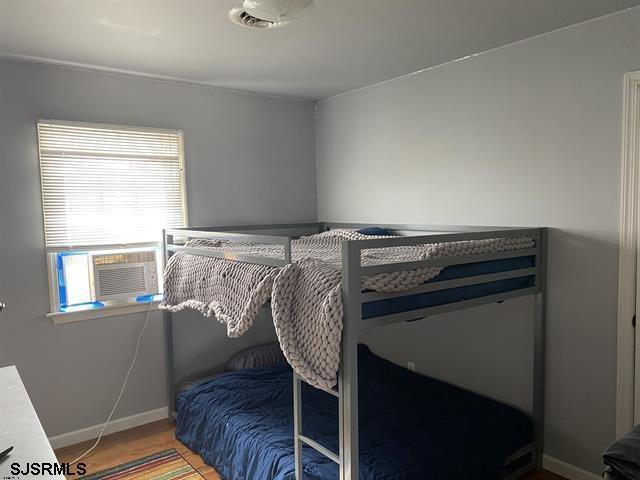 bedroom with cooling unit and hardwood / wood-style flooring