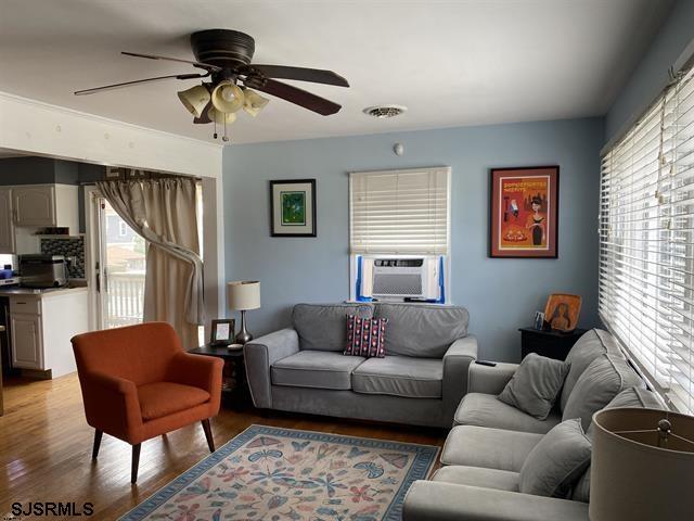 living room with light hardwood / wood-style floors, a wealth of natural light, and cooling unit