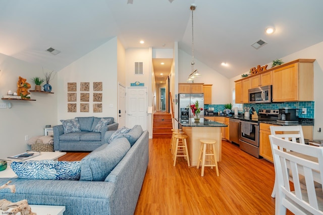 kitchen featuring pendant lighting, a breakfast bar, backsplash, a kitchen island, and stainless steel appliances