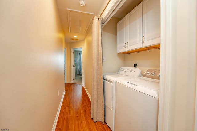 laundry room with cabinets, light wood-type flooring, and washer and clothes dryer