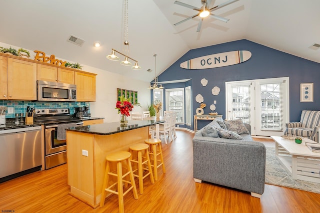 kitchen featuring a center island, a kitchen breakfast bar, hanging light fixtures, appliances with stainless steel finishes, and tasteful backsplash