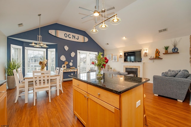 kitchen featuring a tile fireplace, light wood-type flooring, vaulted ceiling, and a healthy amount of sunlight