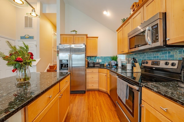 kitchen featuring appliances with stainless steel finishes, backsplash, high vaulted ceiling, light hardwood / wood-style flooring, and dark stone countertops