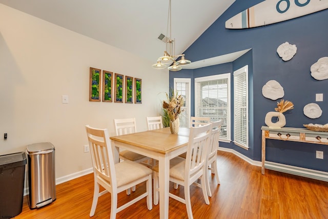 dining room with wood-type flooring, vaulted ceiling, and a notable chandelier