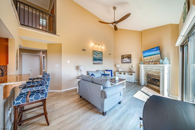 living room with ceiling fan, light hardwood / wood-style floors, and a high ceiling