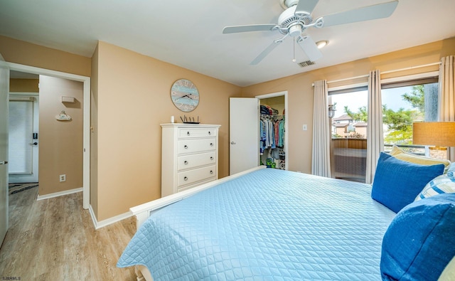 bedroom featuring a closet, a spacious closet, light hardwood / wood-style flooring, and ceiling fan