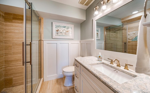 bathroom with vanity, toilet, and a shower with door