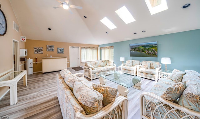 living room with ceiling fan, light wood-type flooring, and lofted ceiling with skylight