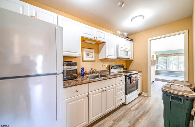 kitchen with white appliances, light hardwood / wood-style floors, white cabinetry, and sink