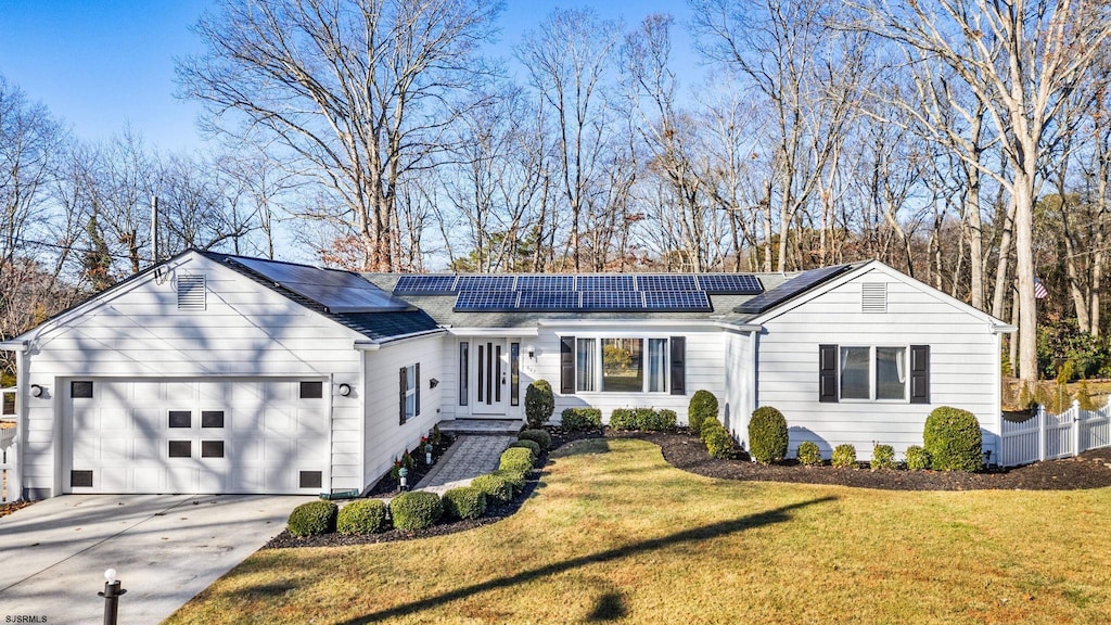 single story home featuring solar panels, a garage, and a front lawn