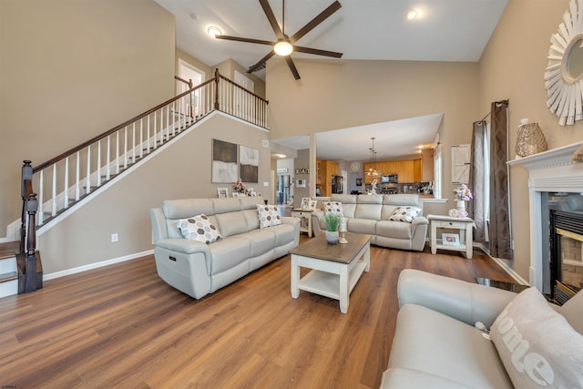 living room featuring hardwood / wood-style floors, ceiling fan, a fireplace, and high vaulted ceiling