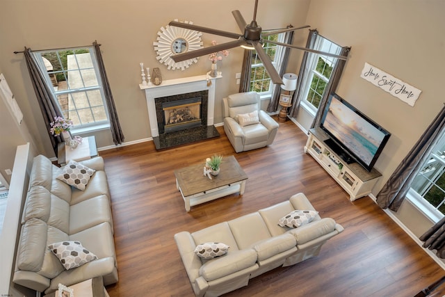 living room featuring dark hardwood / wood-style floors, ceiling fan, and a premium fireplace