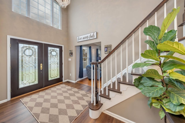 entrance foyer featuring french doors, a towering ceiling, dark hardwood / wood-style floors, and a healthy amount of sunlight