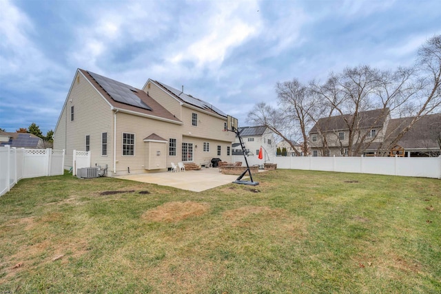 rear view of house with solar panels, a yard, a patio, and cooling unit