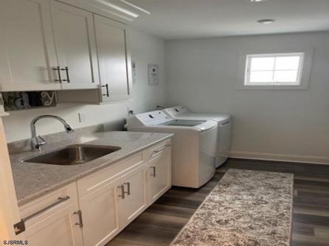 laundry room with dark hardwood / wood-style flooring, sink, washing machine and dryer, and cabinets