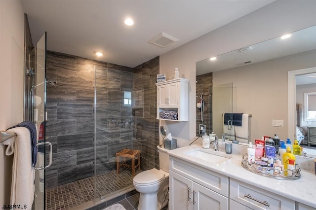 bathroom featuring a shower with door, vanity, and toilet