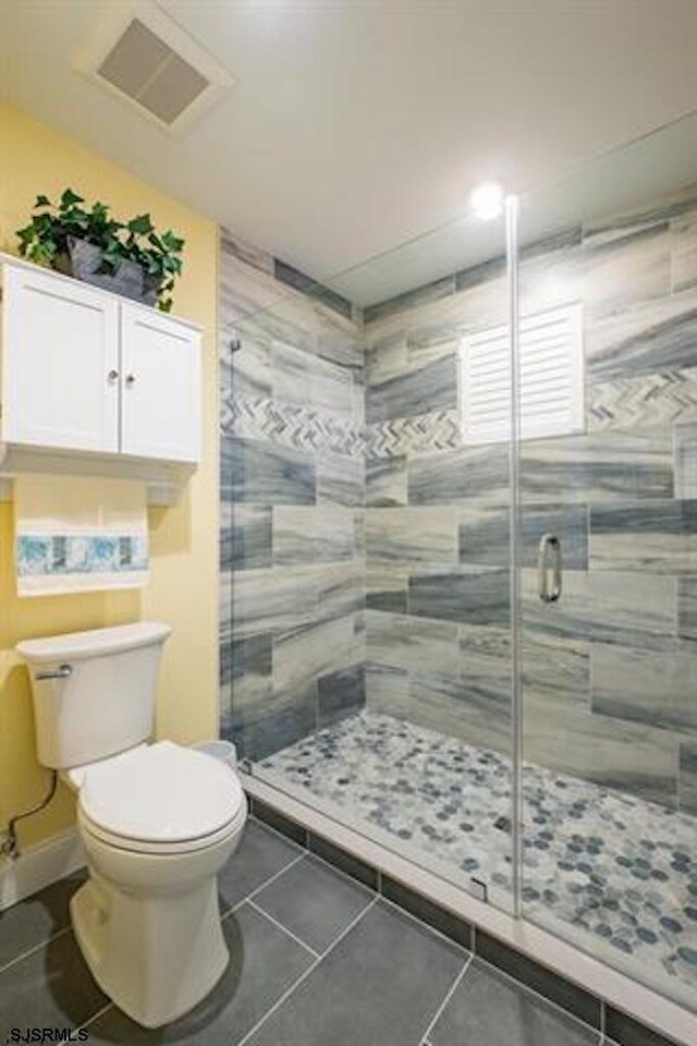 bathroom with a shower with door, tile patterned floors, and toilet