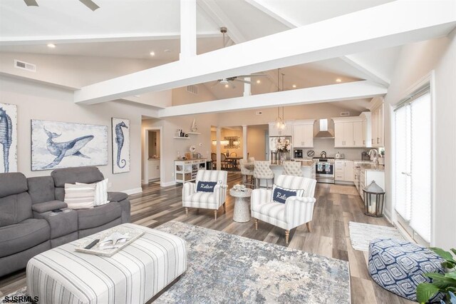 living room with sink, high vaulted ceiling, dark hardwood / wood-style flooring, beamed ceiling, and ceiling fan